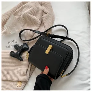 Detail of retro black crossbody bag with gold lock and cute dog leather charm accessory