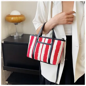 Borsa tote a righe rosse e bianche con manici neri abbinata a un blazer bianco