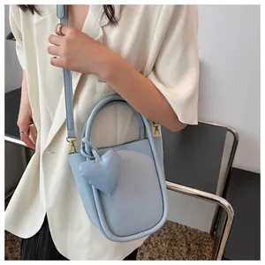 Borsa a secchiello celeste con design a U e ciondolo a cuore indossata con blazer