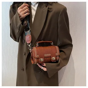 Brown leather crossbody bag with gold studs and vintage pattern wide shoulder strap