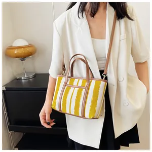 Grande borsa tote a righe con finiture in pelle marrone indossata da una modella con stile
