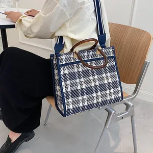 Detailed side view of blue plaid woven tote bag with wooden handle and striped strap