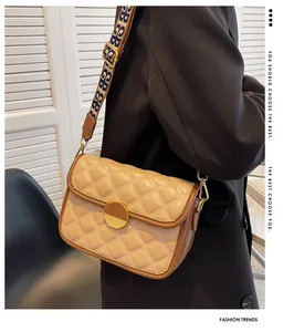 Detail of beige quilted leather crossbody bag featuring a round buckle and jacquard strap