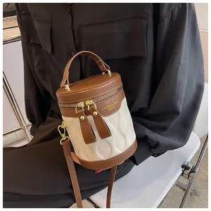 Detail of two-tone bucket bag with wavy texture, gold zippers and branding detail