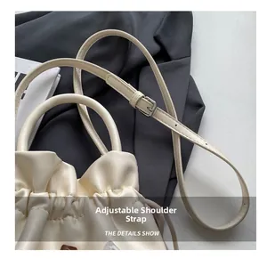 Detail des verstellbaren Kunstleder-Schultergurts mit Silberschnalle an cremefarbener Tasche