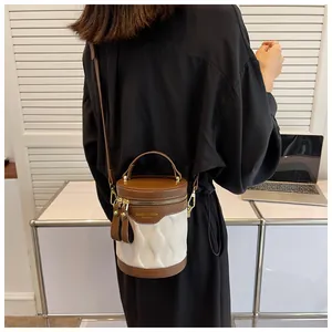 Detail of a mini cylinder bucket bag with contrast brown and white quilted leather