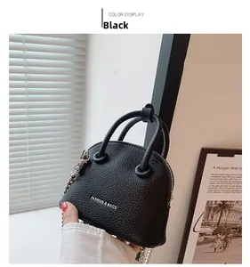 Dettaglio della mini borsa a conchiglia nera con trama litchi e catena d'argento