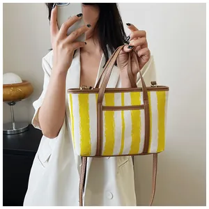 Dettaglio della borsa tote a righe in tela con finiture in ecopelle marrone e tasca esterna