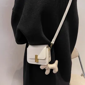 Minimalist cream white leather crossbody bag with gold lock and cute dog charm detail