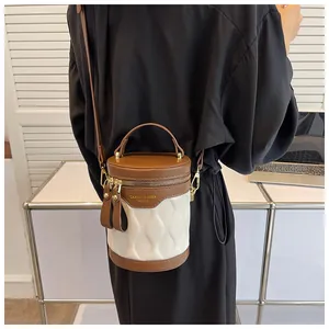Fashionable cylinder bucket bag featuring brown leather trim and white quilted texture
