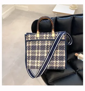 Detail of tweed checkered tote with amber acrylic handles and striped shoulder strap