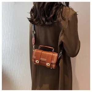 Close-up of brown vintage leather crossbody bag with ethnic strap and metal rivet details