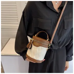 Detail of color-block bucket bag with brown leather and white wave-textured panels