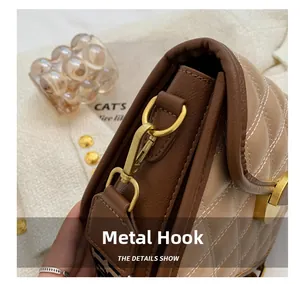 Detail of matte gold hardware hook and quilted stitching on brown faux leather bag