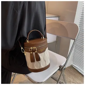Detail showing contrast wave-texture quilting and brown leather on the bucket bag