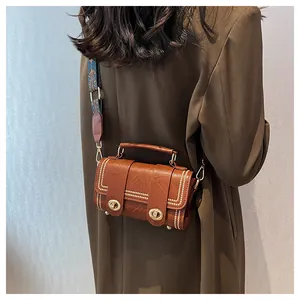 Brown faux leather crossbody bag with retro jacquard strap and stud details worn by model