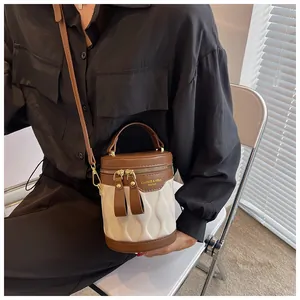 Close-up of a mini bucket bag with wavy quilting and leather straps worn by a model