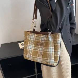 Borsa tote in tweed a quadri verde e blu con manici in pelle indossata da una modella