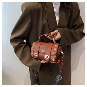 Detail view of brown vintage cylindrical bag with metal rivets and ethnic woven strap