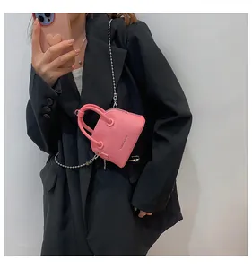 Dettaglio della pelle rosa a grana litchi e della catena in metallo sulla mini borsa