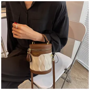 Detail of a brown and white contrast cylinder bucket bag with wavy quilted faux leather texture