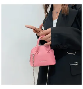 Dettaglio mini borsa a conchiglia rosa con trama litchi e catena argento su modella