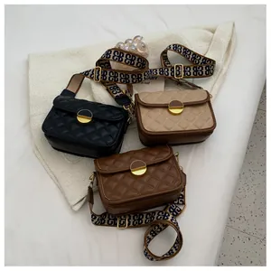 Detailed view of quilted faux leather crossbody bags with metal locks and patterned straps