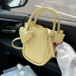 Borsa a secchiello in pelle PU giallo chiaro minimalista con ciondolo a cuore