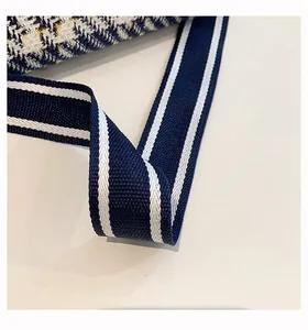 Detail of navy blue striped shoulder strap and plaid woven texture on tote bag