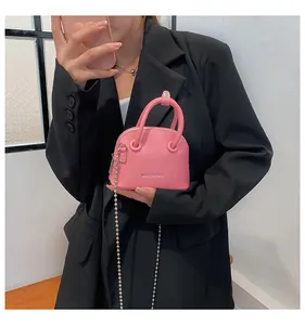 Mini borsa a conchiglia rosa con trama litchi e catena su un blazer nero