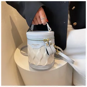 Detail of blue and beige bucket bag with wave quilted texture and gold metal hardware