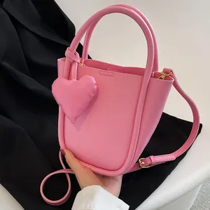 Borsa a secchiello in pelle rosa da donna con ciondolo a cuore e tracolla