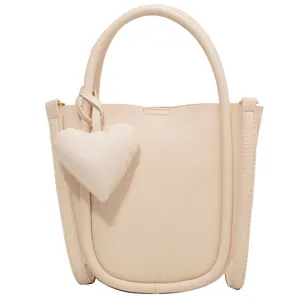 Borsa a secchiello beige in finta pelle con ciondolo a cuore e manico curvo da donna
