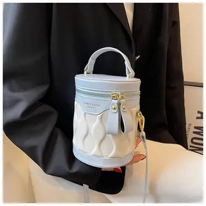Close-up of minimalist contrast color bucket bag with wave quilted texture and gold logo