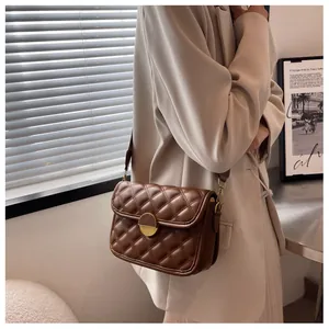 Detail of dark brown quilted shoulder bag with gold metal lock and leather texture
