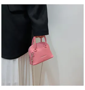 Dettaglio mini borsa a conchiglia rosa con trama litchi, catena argento e manico