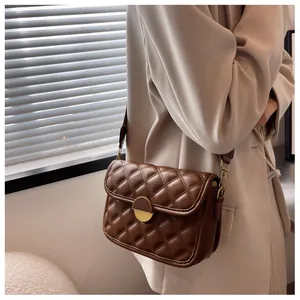 Close-up of quilted pattern and gold metal rotary lock on brown leather crossbody bag