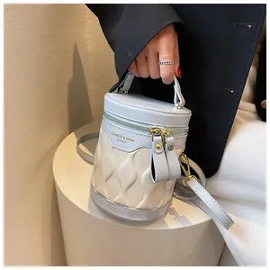 Detail of blue and beige bucket bag featuring a wavy quilted design and gold dual zippers