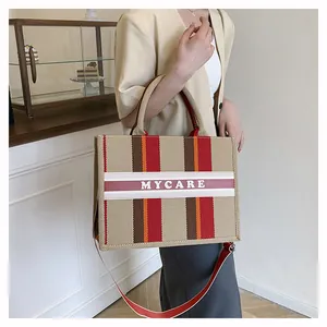 Dettaglio della borsa tote in tela a scacchi con strisce colorate e scritta Mycare