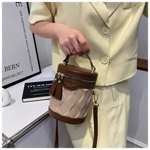 Detail of a brown leather bucket bag featuring beige wave textures and gold hardware
