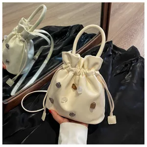 Detailansicht der cremefarbenen Beuteltasche mit bunten Steinen und Kordelzug