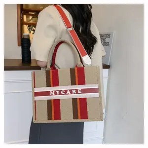Dettaglio della borsa tote in tela a righe con stampa MYCARE e ampia tracolla regolabile