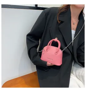 Mini borsa a conchiglia rosa con trama litchi indossata da modella in blazer nero