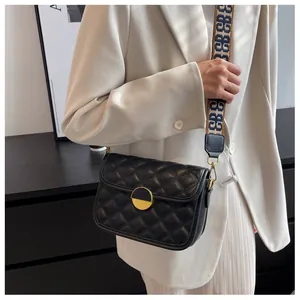 Close-up of black quilted crossbody bag featuring a wide jacquard strap on a model
