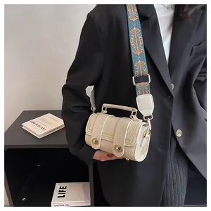 Detail of cream barrel bag showing leather texture and patterned jacquard strap