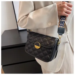 Close-up of black quilted crossbody bag with stylish patterned wide shoulder strap