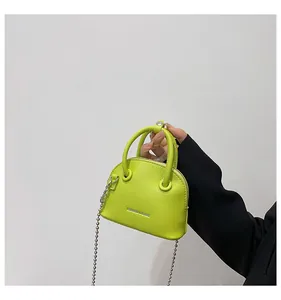 Dettaglio mini borsa a conchiglia verde neon con trama litchi e tracolla a catena