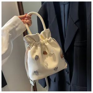 Detail der cremefarbenen Beuteltasche mit bunten Schmucksteinen und Falten-Design