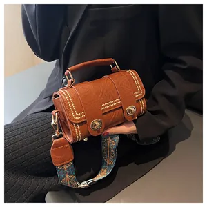 Detail of brown faux leather shoulder bag with gold rivets and bohemian print strap