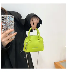 Dettaglio mini borsa verde neon con trama a grana e tracolla a catena argento